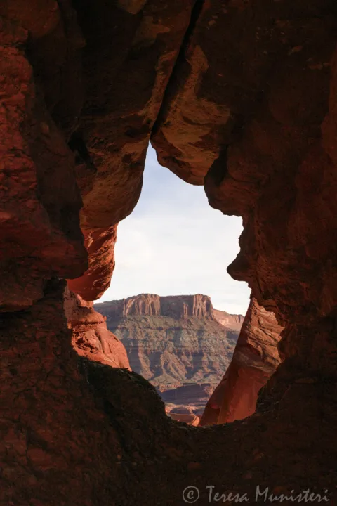View through a sandstone window onto distant mesas above the Colorado River
