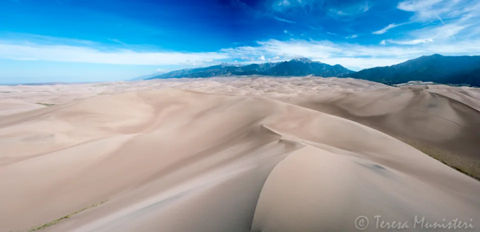 Wind-carved sand dunes under a deep blue sky