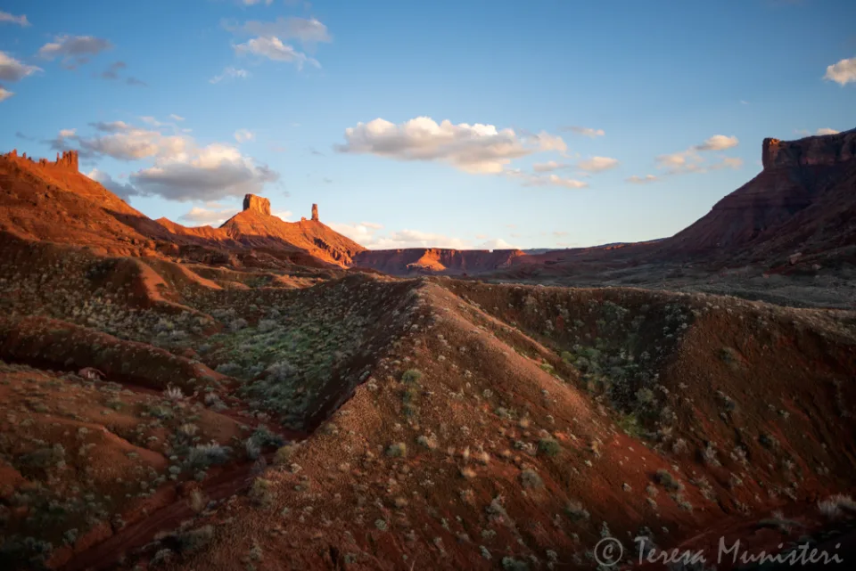 Castleton Tower and the Priest and Nuns above a red dirt road at sunrise
