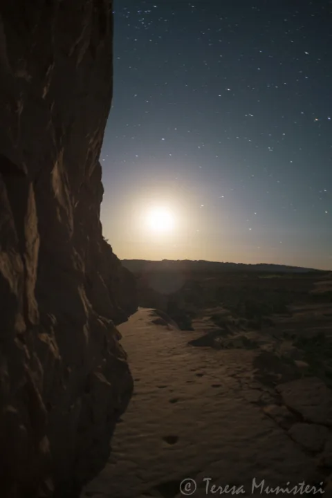 Moonrise over a canyon seen from a dark alcove