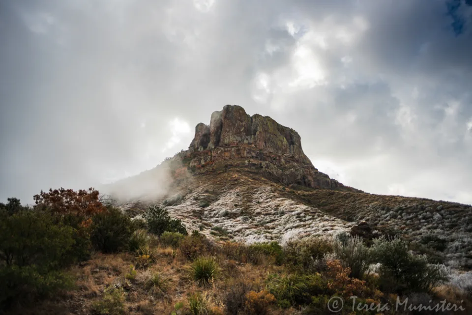 Clouds breaking over a snow-dusted desert peak
